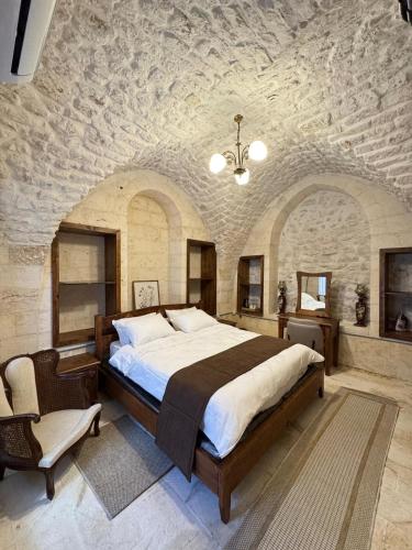 a bedroom with a large bed and a stone wall at Antikhan Han Yusufpaşa in Urfa