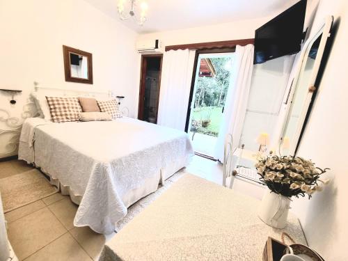 a white bedroom with a bed and a window at Pousada Boutique Rancho Campanário in Rancho Queimado