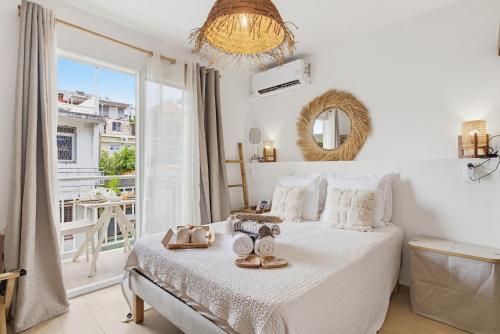 a white bedroom with a bed and a large window at Appart'hôtel DLOKOKO Sainte Luce centre in Sainte-Luce