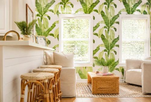 a living room with a plant mural on the wall at The Palm Beach House - Tropical in Palm Beach