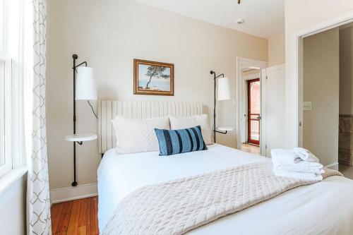 a white bedroom with a large white bed with blue pillows at Red Bud Suite in Staunton