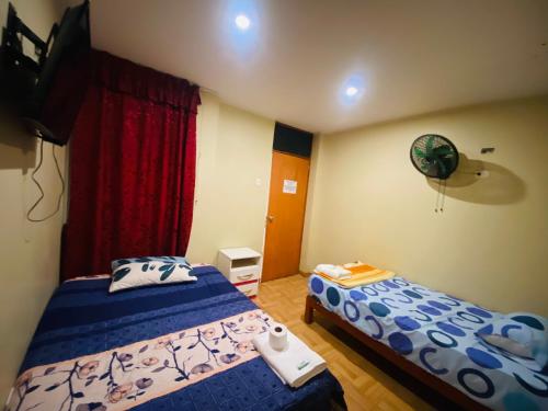a bedroom with two beds and a television in it at Hospedaje De Joce in Nazca