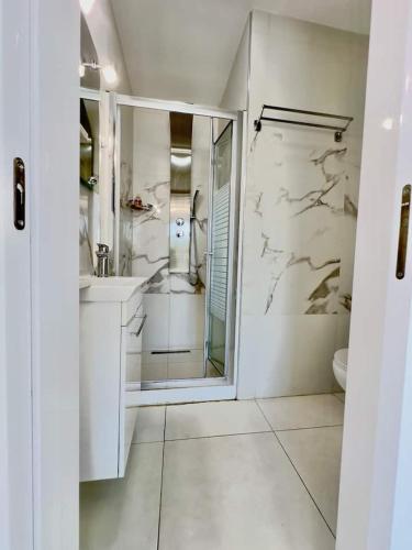 a white bathroom with a shower and a sink at Lumière Retreat 2 in Larnaca