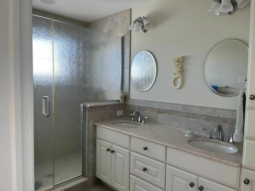 a bathroom with two sinks and a glass shower at Bayside Gem in Beach Haven Crest