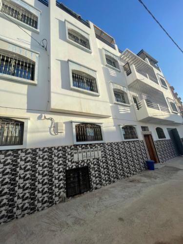 a white building with windows and a wall at Coastal Haven Surf Morocco in Aourir