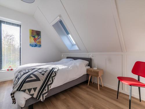 a bedroom with a bed and a red chair at Fantastic villa located by a lake in Sint Nicolaasga