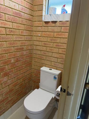 a bathroom with a toilet and a brick wall at Entire 2 bedrooms unit in Geraldton