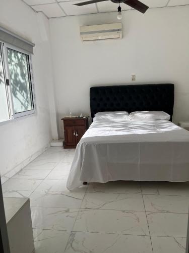 a white bedroom with a bed and a window at Casa Quinta La Jaula in Isla Paracao