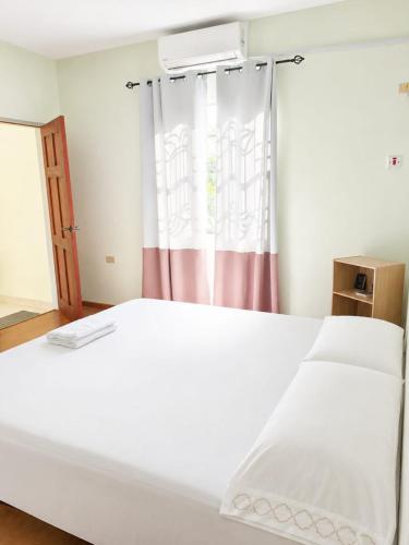 ein weißes Bett in einem Zimmer mit Fenster in der Unterkunft Cozy Corner in San Fernando