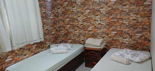 two beds in a room with a brick wall at Apartamento Capitólio D'Loren dos lagos 4º andar in Capitólio