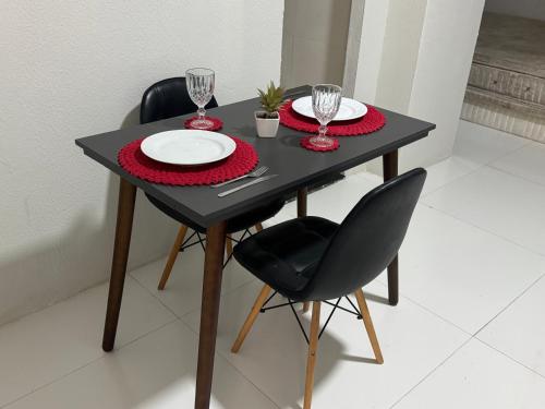 a black table with two plates and wine glasses on it at Flat Lucidata in Feira de Santana