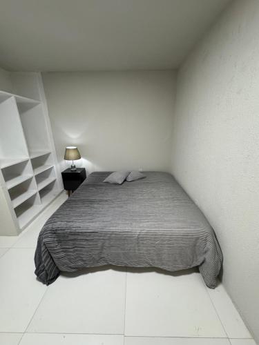a white bedroom with a bed and a lamp at Flat Lucidata in Feira de Santana