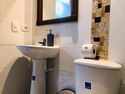 a bathroom with a sink and a toilet and a mirror at GV Aparta Suites Apto Familiar Amplio y Luminoso in Chía
