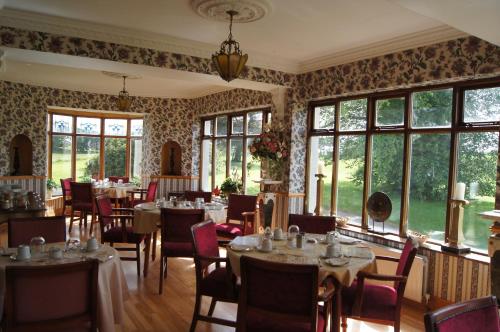 a dining room with tables and chairs and windows at Cavangarden House in Ballyshannon