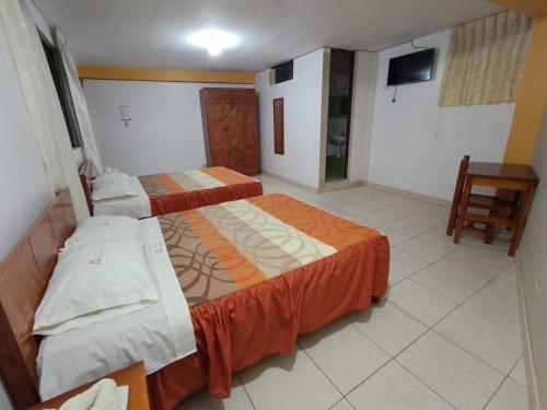 a hotel room with two beds and a television at Hotel Pradera de los Celajes in Cajamarca