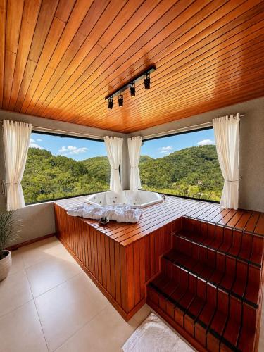a large bathroom with a tub and a large window at Chalés Aframe com café da manhã artesanal, 39km de Pomerode, Hidromassagem privativa, silenciosos em meio a natureza, lagoa para pesca esportiva in Massaranduba