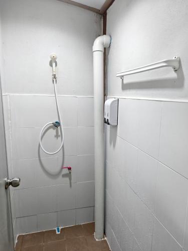 a shower in a bathroom with white tiles at Happy Homey Hostel in Suratthani