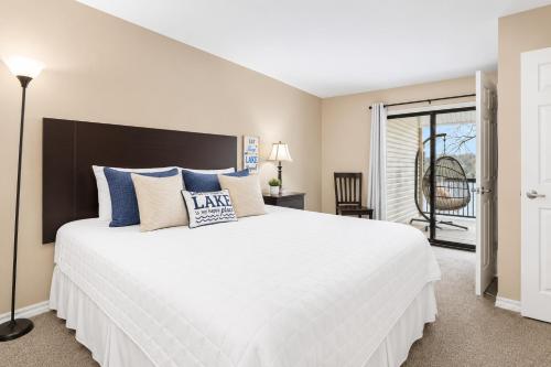 a bedroom with a large white bed with blue pillows at The Perch at Kimberling Crossing in Kimberling City
