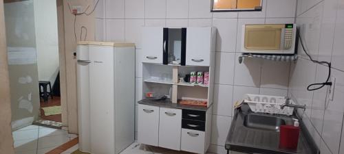a small kitchen with a refrigerator and a microwave at Assel Pousada Xaxim in Curitiba
