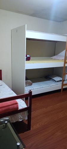 a room with two bunk beds and a wooden floor at Assel Pousada Xaxim in Curitiba