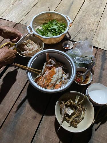 a group of bowls of food on a wooden table at Cactos Floating House Experience on Island in Lai Sơn