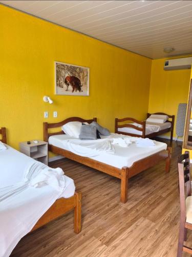 two beds in a room with yellow walls at ECO CHALÉ PARK CACHOEIRAS in Presidente Figueiredo