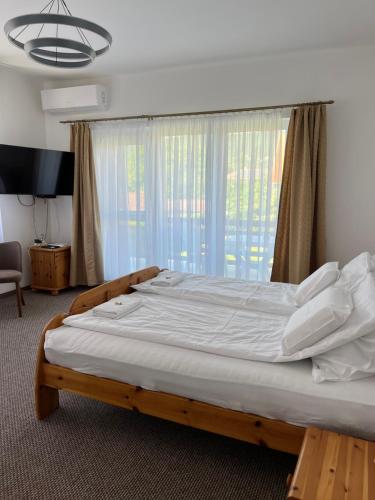 a large bed in a room with a large window at Katalin vendégház felső szint in Visegrád