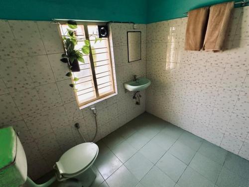 a bathroom with a toilet and a sink and a window at Mass Bungalow in Tindummal