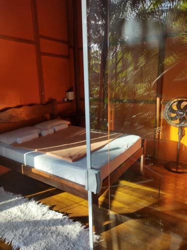 a bed in a room with a glass wall at Chale Tupi da Pedra in Trindade