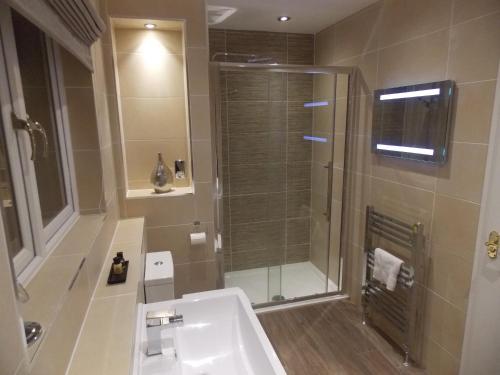 a bathroom with a shower and a white sink at Springfield Lodge Bed and Breakfast in Stirling