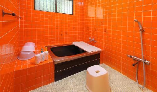 an orange tiled bathroom with a sink and a toilet at ゲストハウス両浜 in Kushimoto
