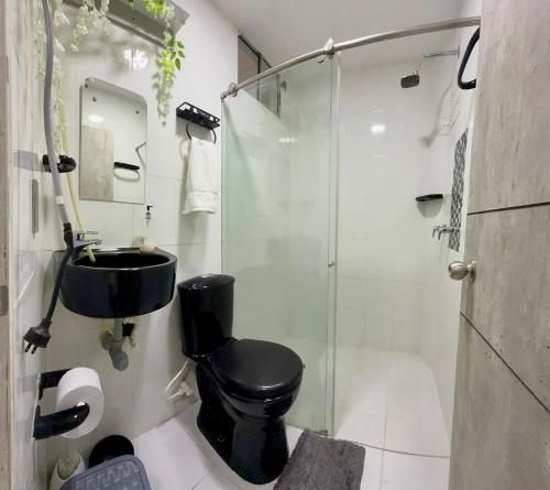 a bathroom with a black toilet and a glass shower at Apartamentos cerca al centro de Cali in Cali