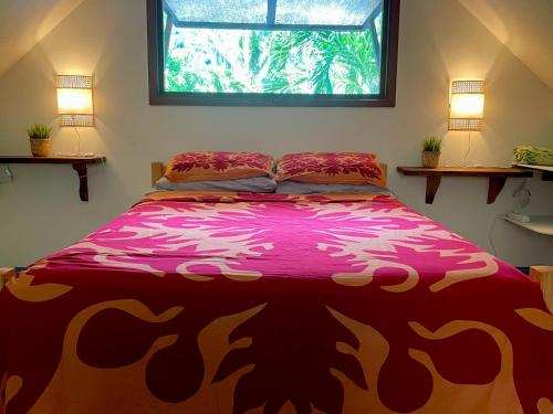 a bedroom with a bed with a pink comforter and a window at Franky's Fare in Fare