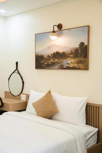 a bedroom with a bed with a painting on the wall at Black Win Hotel Phu Yen in Mỹ Hòa (1)