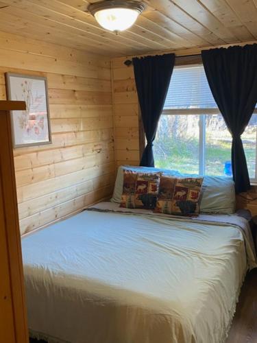 a bed in a log cabin with a window at Ak backcountry retreat in Kenai