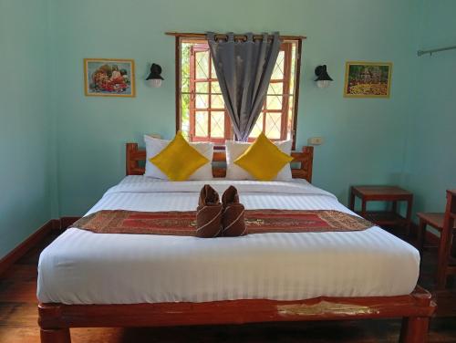 a bed with a pair of shoes sitting on it at MG Guesthouse in Sukhothai