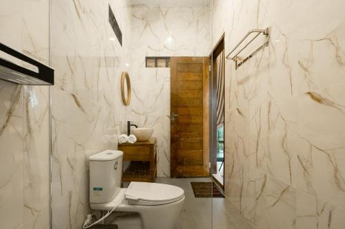 a white bathroom with a toilet and a sink at Alam Kasih Villa in Tampaksiring