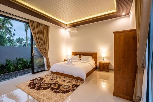 a bedroom with a bed and a large window at Alam Kasih Villa in Tampaksiring