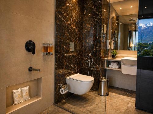 a bathroom with a toilet and a glass shower at Aachman Riviera Valley dharamshala by NAINA STAYCATION in Dharmsāla