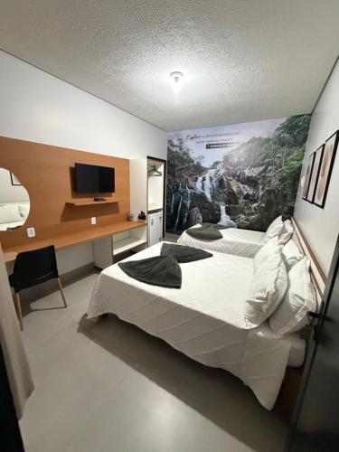 a bedroom with a large bed with a painting on the wall at Alphaville Hotel in Barra do Bugres
