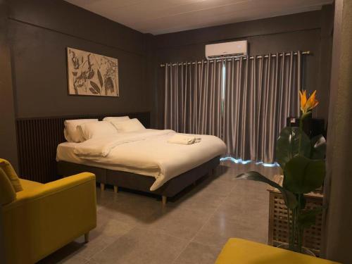 a bedroom with a bed and a yellow chair at The Mansion Pakchong in Pak Johng
