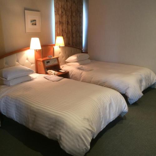 a hotel room with two beds and a laptop on a table at Hotel Crown Hills Koriyama in Koriyama