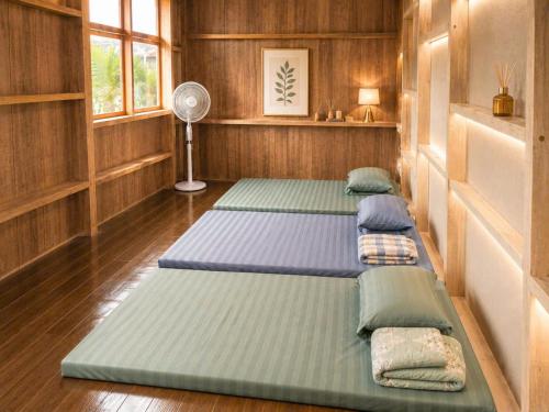 three beds in a room with wooden walls and a fan at BângGlamping in Hue