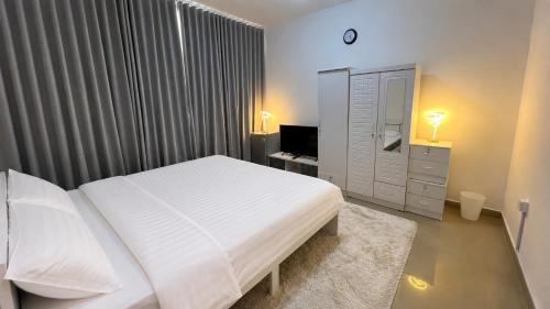 a bedroom with a white bed and a television at Banny Homes - Cozy Suite Apartment - Downtown in Abu Dhabi