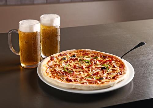 a pizza on a table with two glasses of beer at Shilla Stay Gwanghwamun Myeongdong in Seoul