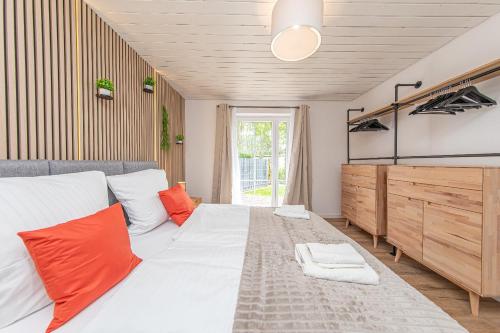 a bedroom with a large white bed with orange pillows at Boutique 54° Nord in Büsum