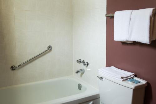 a bathroom with a white tub and a toilet and a sink at City Centre Motel older building in Hope