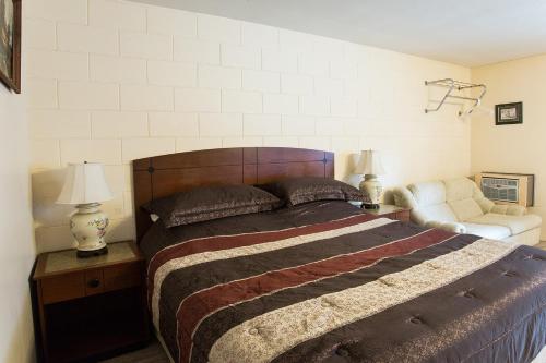 a bedroom with a bed and a couch and a chair at City Centre Motel older building in Hope