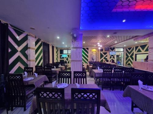 a dining room with tables and chairs and purple lighting at Hotel Biaspushp Dalhousie in Banikhet