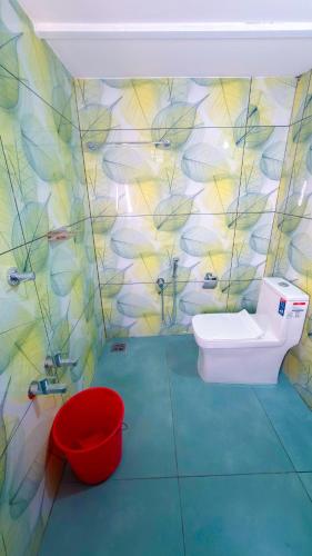 a bathroom with a toilet and a red bucket at Thushara Homestay in Kozhikode
